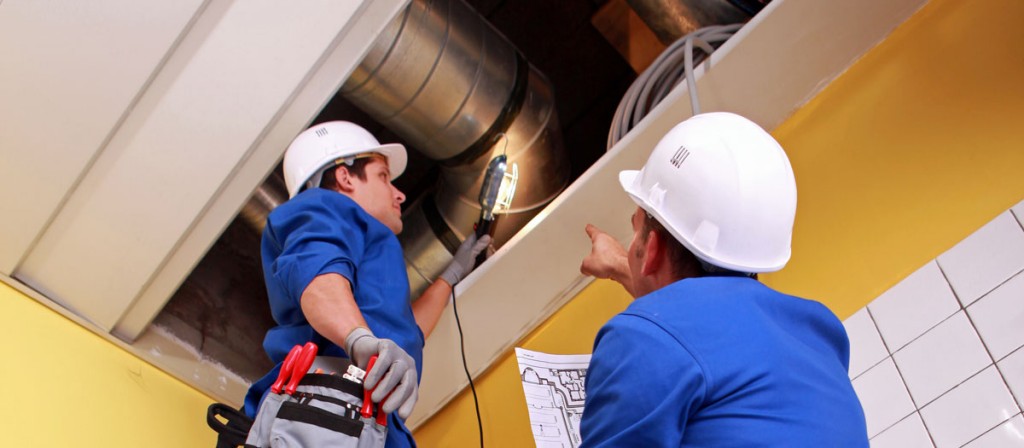 Two men looking at their ventilation system in the ceiling to illustrate Prevent Heat Stroke With Industrial Ventilation and heat removal equipment.